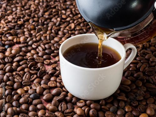 Cup and pot of coffee on coffee beans background