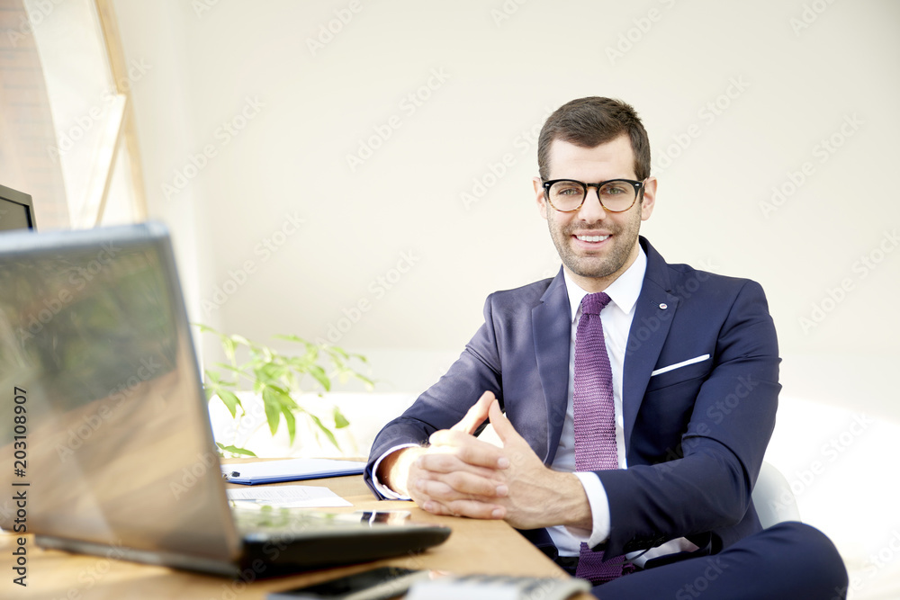 Businessman using laptop. Portrait of young financial assistant businessman wearing suit while sitting at office desk and working on financial report. Businessman using laptop. Portrait of young financial assistant businessman wearing suit while sitting at office desk and working on financial report.