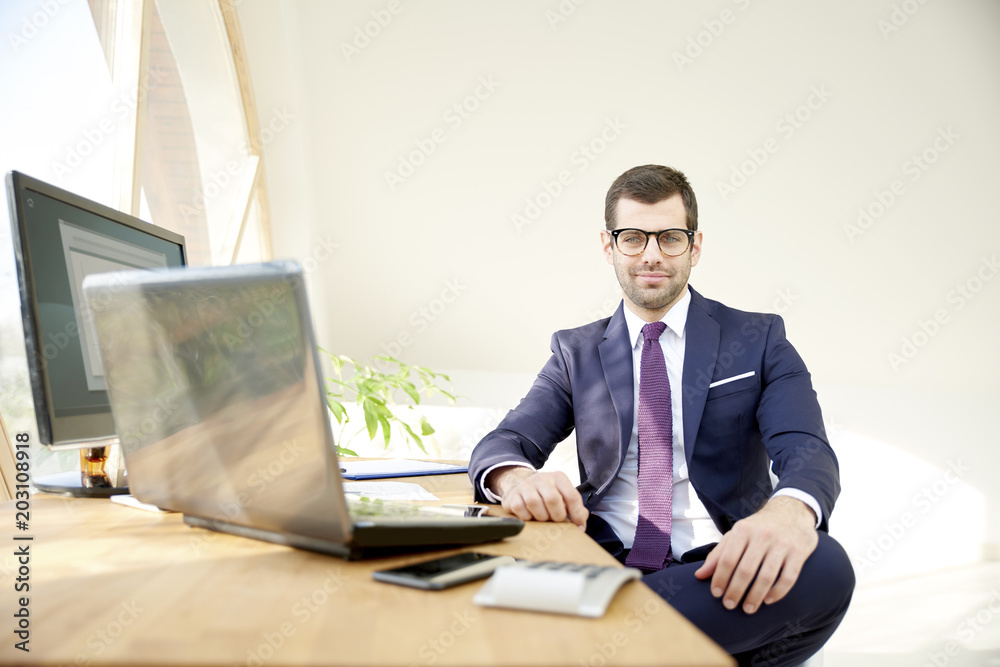 Businessman using laptop. Portrait of young financial assistant businessman wearing suit while sitting at office desk and working on financial report. Businessman using laptop. Portrait of young financial assistant businessman wearing suit while sitting at office desk and working on financial report.