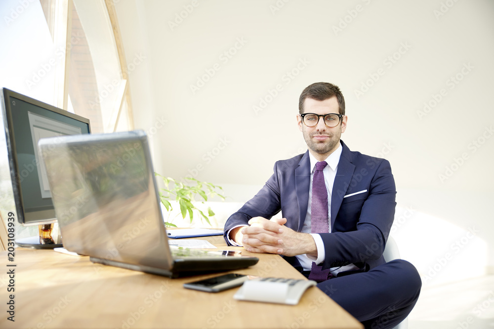 Businessman using laptop. Portrait of young financial assistant businessman wearing suit while sitting at office desk and working on financial report. Businessman using laptop. Portrait of young financial assistant businessman wearing suit while sitting at office desk and working on financial report.