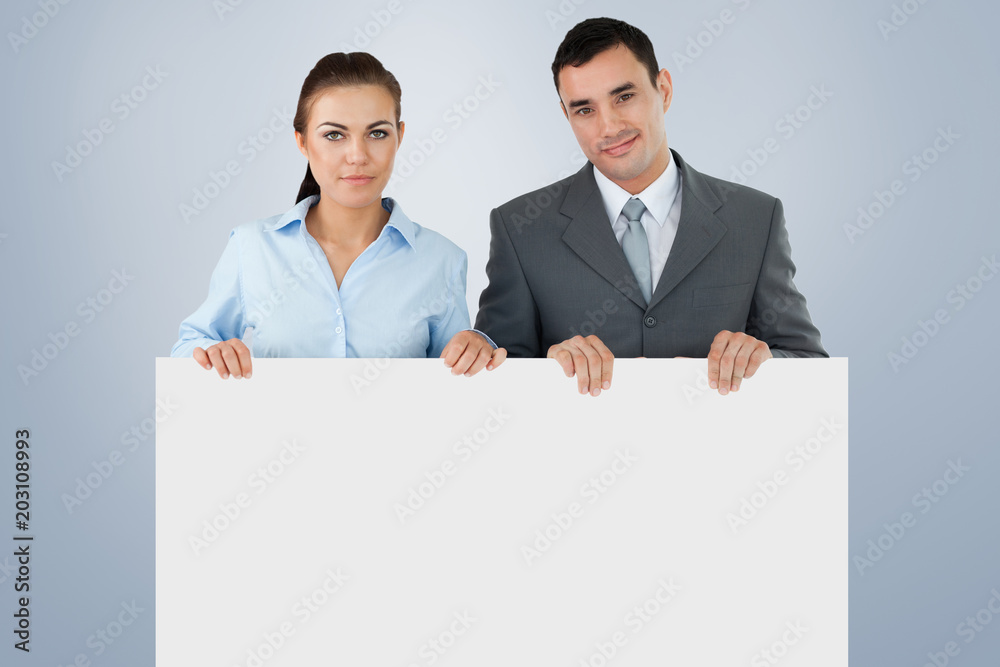Business partners holding sign against grey vignette Business partners holding sign against grey vignette
