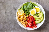 Healthy salad bowl with chickpeas, goose meat , tomatoes, avocado, lemon and spinach