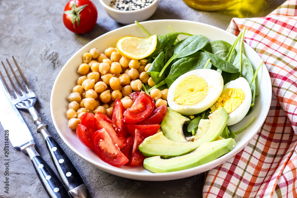 Healthy salad bowl with chickpeas, goose meat , tomatoes, avocado, lemon and spinach