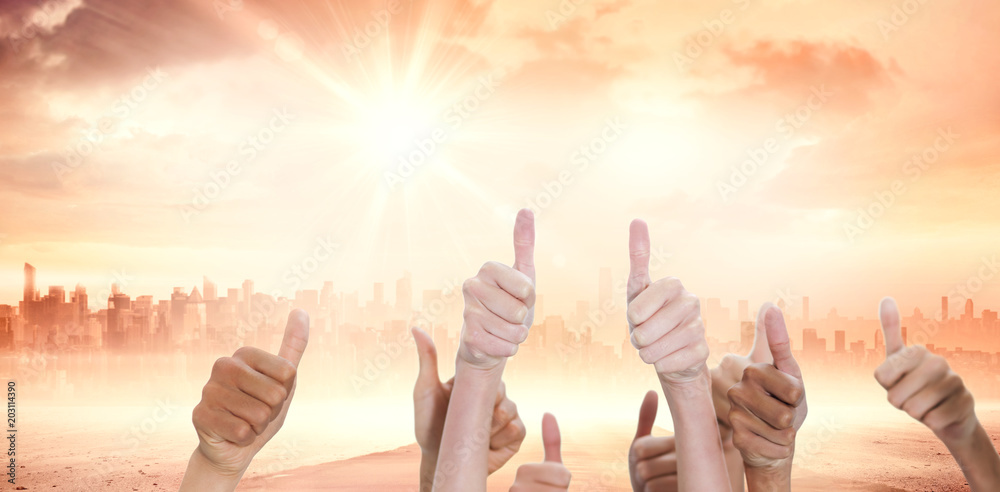 Thumbsup against sun shining over city