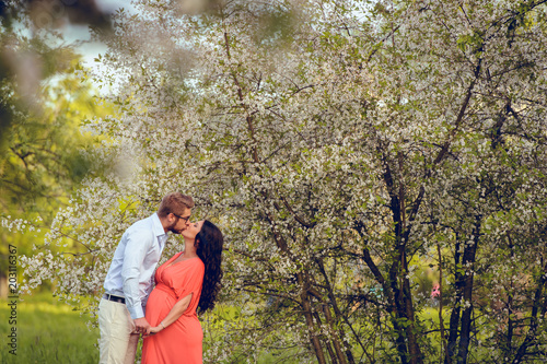Romantic portrait of young smiling happy couple of lovely future parents during sunset on nature apple tree background in the city park. Pregnancy pregnant future mother photoshoot. Motherhood photo © ANR Production