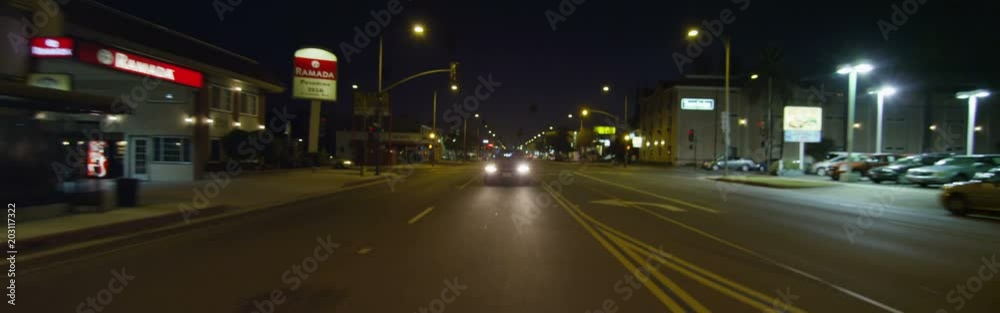 Rear view of a Driving Plate: Car travels on East Colorado Boulevard in Pasadena, California at night, crossing Craig Avenue, pausing near Sierra Madre Boulevard, and continuing on to make a left turn at Sunnyslope Avenue.