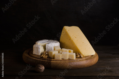 Assorted cheeses on round wooden board plate