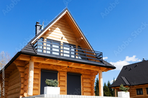 Nice wooden house with a balcony, on a hill under a blue sky