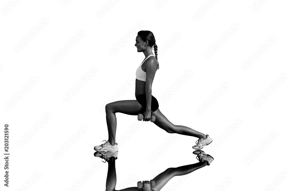 Fit woman doing weighted lunges on the beach against mirror