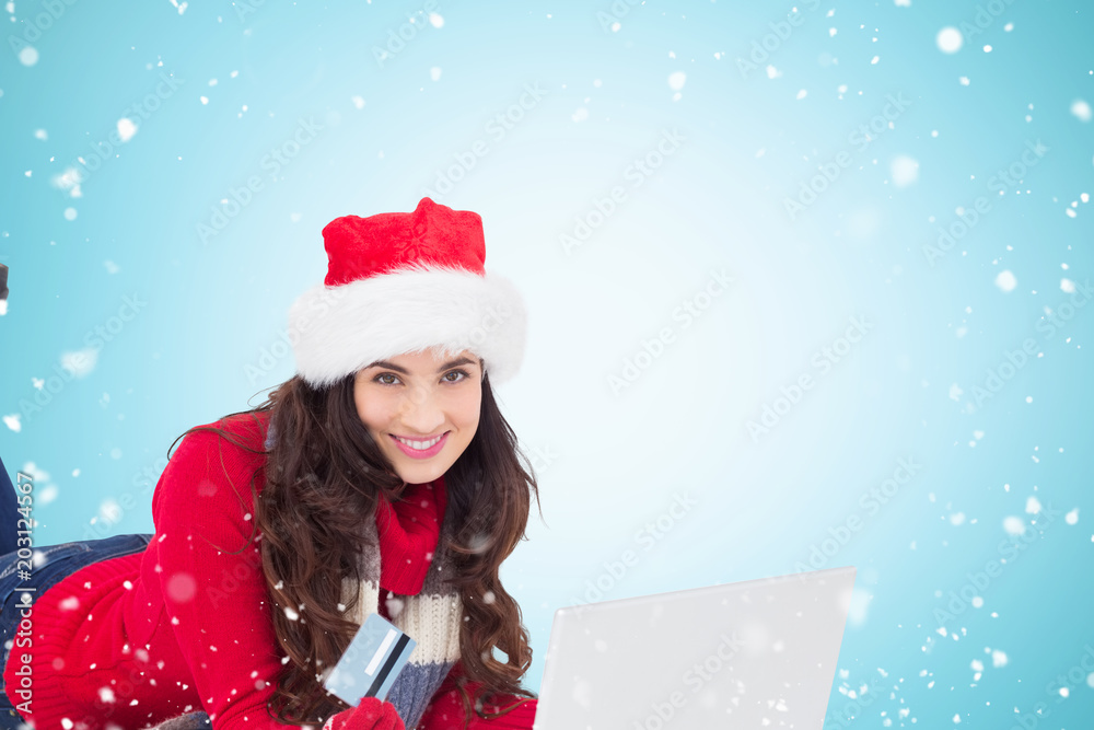 Festive brunette shopping online with laptop against blue vignette