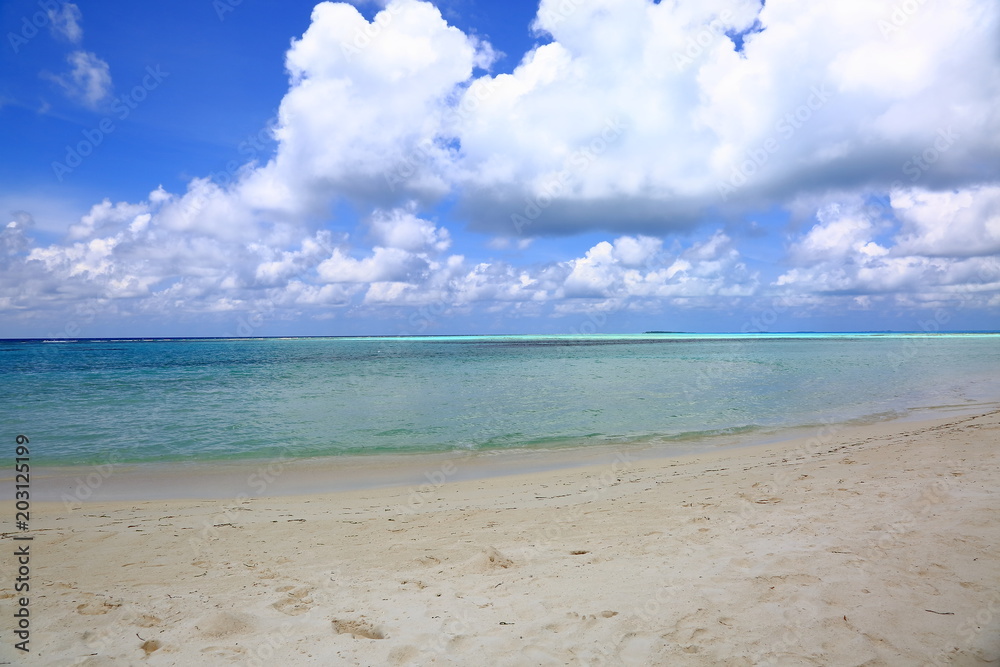Beautiful view of white sand beach. Turquoise water and blue sky with white clouds. Indian Ocean, Maldives.