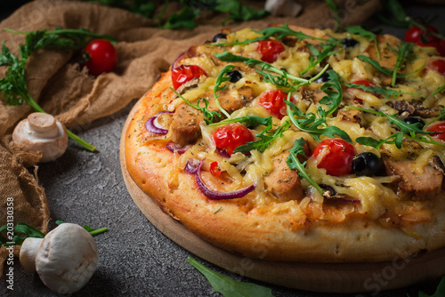 Pizza with chicken, arugula, cheese and onions on wooden rustic table. Top view