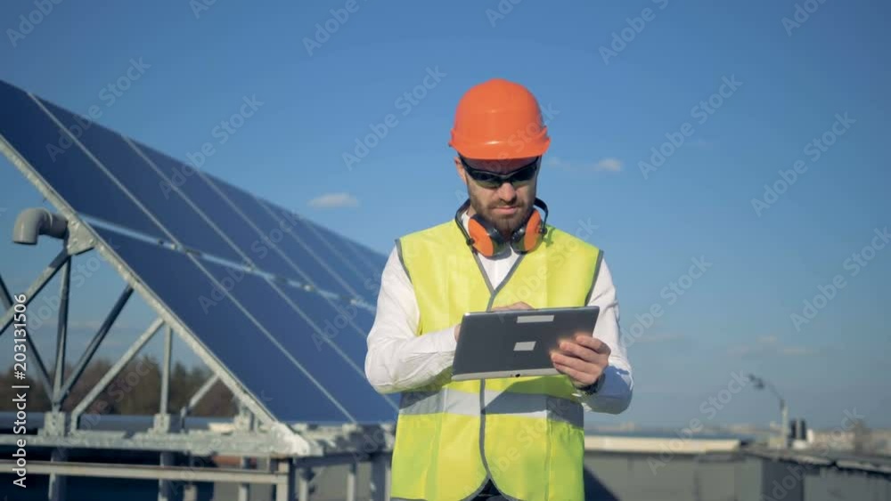 A worker uses tablet, counting solar panels on a roof. 4K. A worker uses tablet, counting solar panels on a roof. 4K.