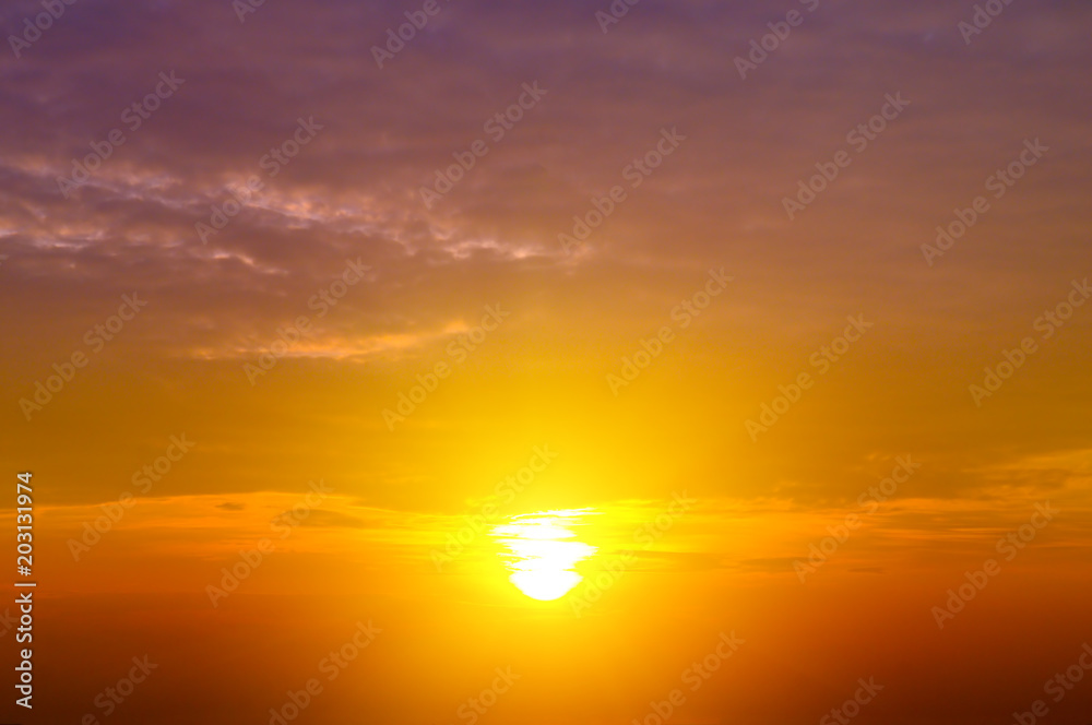 Cloudy sky and bright sun rise over the horizon.