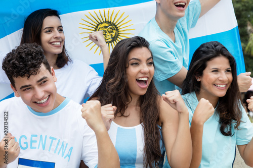 Group of cheering soccer fans from Argentina with argentinian flag photo