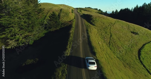 Wallpaper Mural Aerial view of car driving down country road through rural rolling hills at sunset Torontodigital.ca