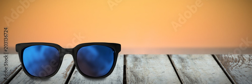 Close-up of sunglasses against waves crashing at sunset