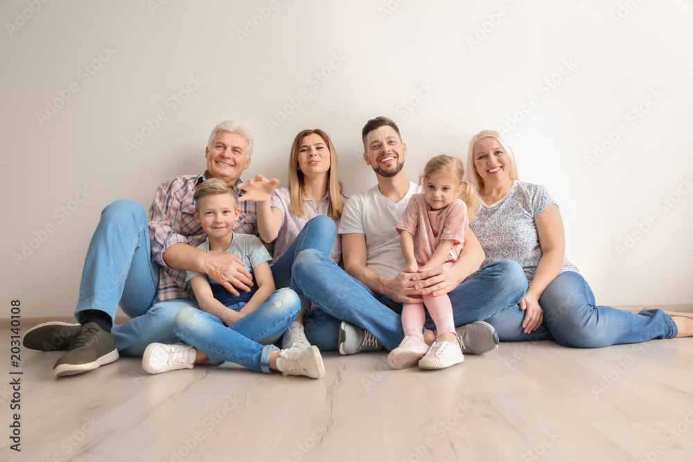 Happy family with cute kids sitting on floor near light wall Happy family with cute kids sitting on floor near light wall
