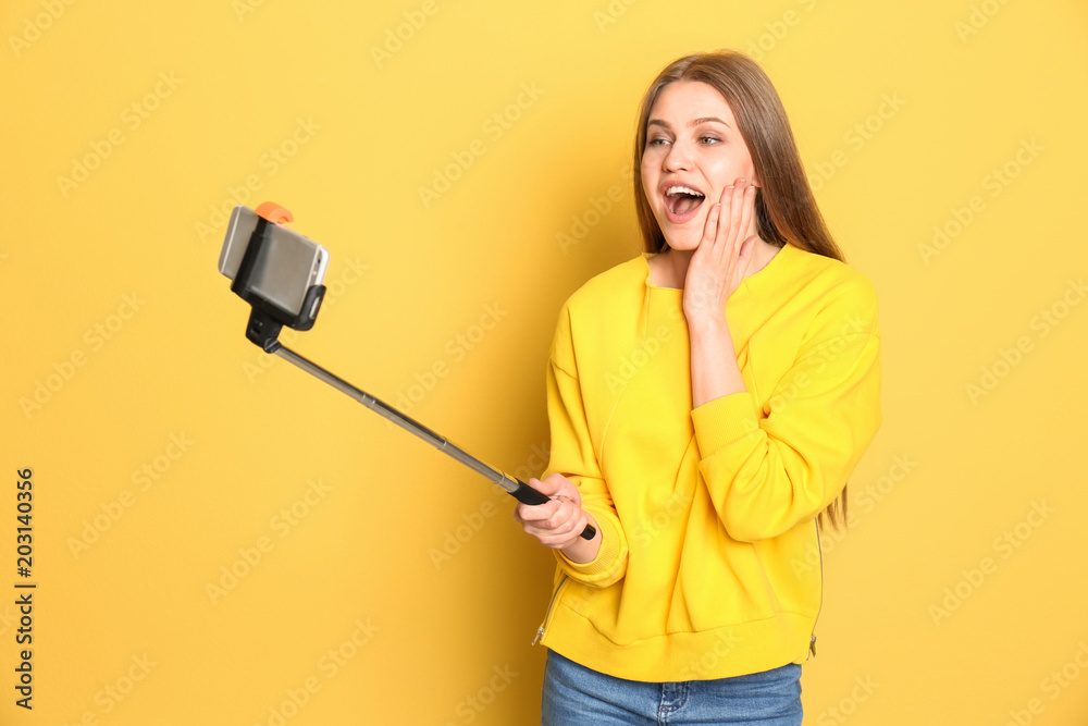Young beautiful woman taking selfie against color background Young beautiful woman taking selfie against color background