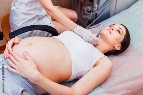 Pregnant Young Woman Doing Thyroid Gland Ultrasound Examination At Hospital. Close Up photo