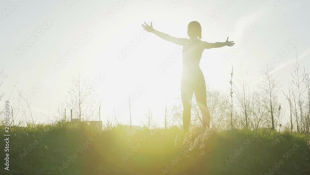 Young pretty sportswoman is engaged in fitness in nature. Silhouette of a girl doing exercise against the sky. General plan. Steadicam shot Young pretty sportswoman is engaged in fitness in nature. Silhouette of a girl doing exercise against the sky. General plan. Steadicam shot