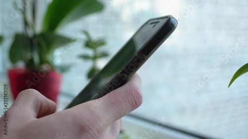 Closeup hand unlocking and holding a smartphone on blurred background