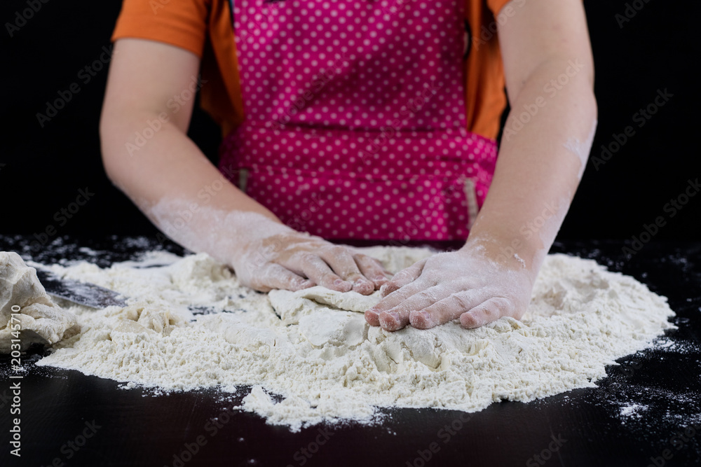 Kneading dough on a black table in a bakery. Baker's hands preparing dough for bread. Kneading dough on a black table in a bakery. Baker's hands preparing dough for bread.