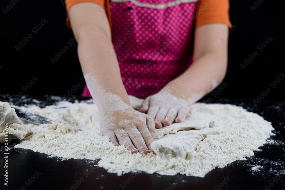 Kneading dough on a black table in a bakery. Baker's hands preparing dough for bread.