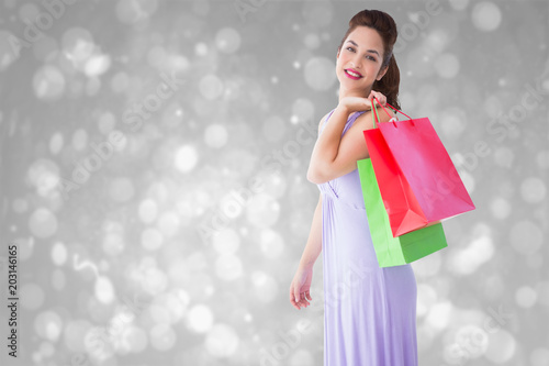Elegant brunette posing with shopping bags against grey abstract light spot design