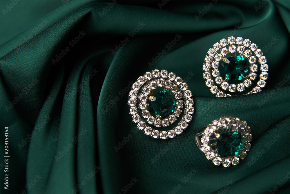 Emerald ring and pair of diamond earrings in gold, wedding jewelry with luxury gift box , close-up. Selective focus Emerald ring and pair of diamond earrings in gold, wedding jewelry with luxury gift box , close-up. Selective focus