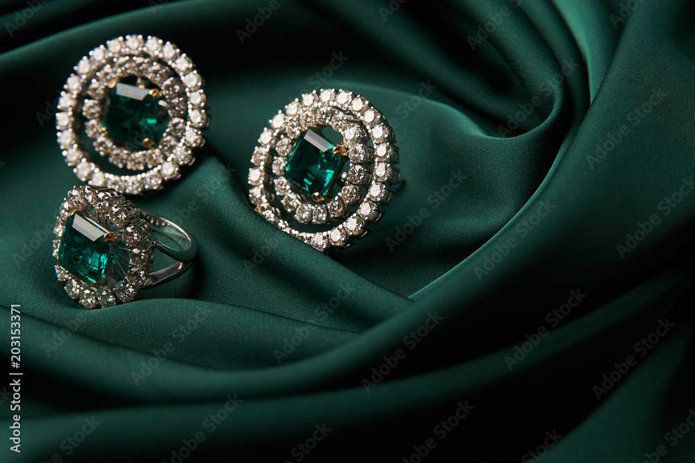 Fototapeta premium Emerald ring and pair of diamond earrings in gold, wedding jewelry with luxury gift box , close-up. Selective focus