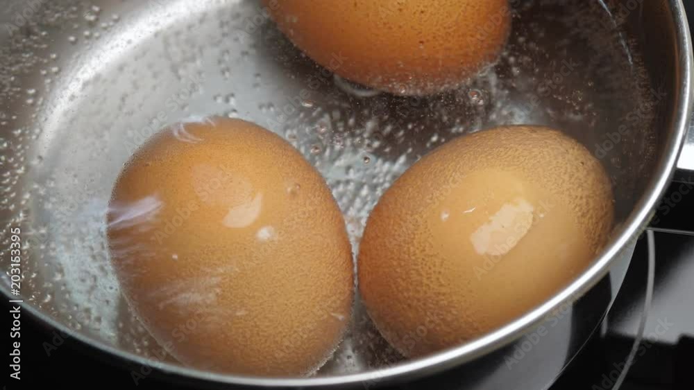 Chicken eggs boiling in stainless steel pan