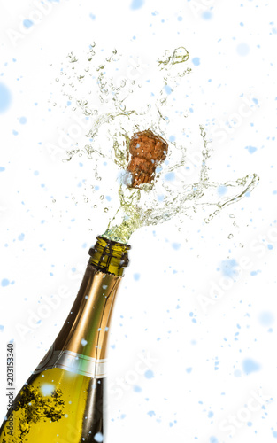 Snow falling against bottle of champagne popping