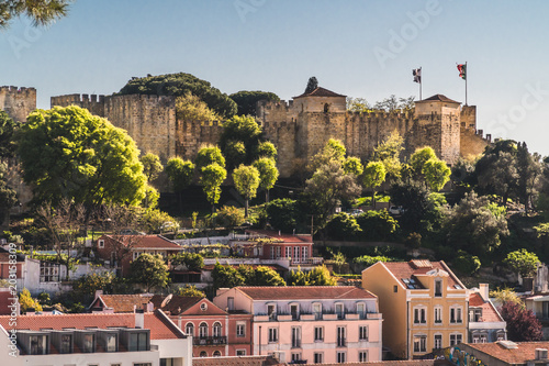 The famous medieval castle of Saint George on top of a hill in the city of Lisbon, Portugal. Below are some more modern buildings in the city. photo