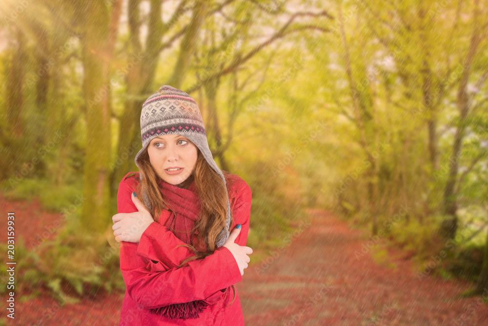 Cold redhead wearing coat and hat against peaceful autumn scene in forest