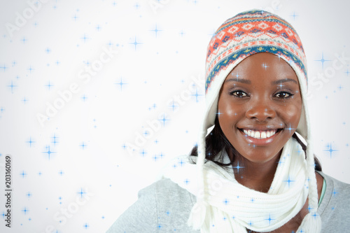 Smiling young woman with winter clothes on against twinkling stars