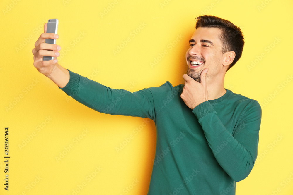 Young handsome man taking selfie against color background Young handsome man taking selfie against color background