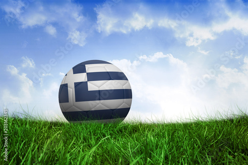 Football in greece colours on field of grass under blue sky