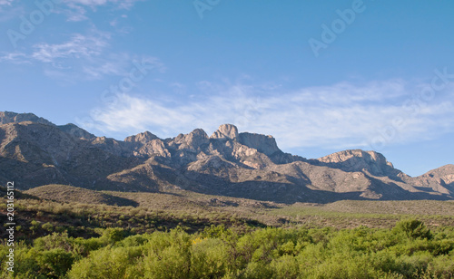 A distant mountain range in the Sonoran desert with a beautiful blue sky and a lush green valley