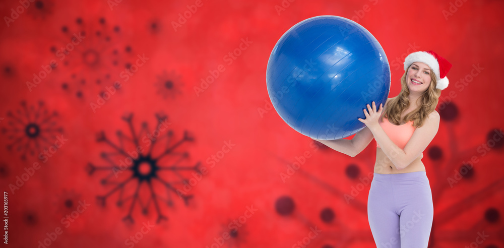 Naklejka premium Smiling blonde woman holding exercise ball against red snow flake background
