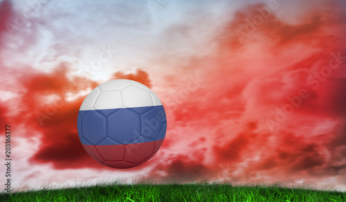 Football in russia colours against green grass under red cloudy sky © vectorfusionart