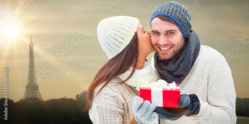 Winter couple holding gift against eiffel tower photo