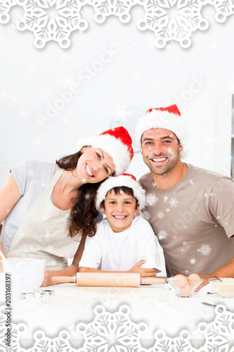 Happy family baking christmas cookies together against snow falling