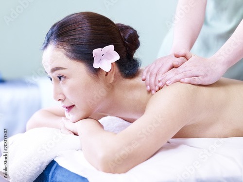 young asian woman receiving massage in spa salon