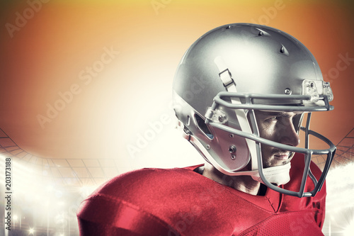 Confident American football player in red jersey looking away against rugby stadium