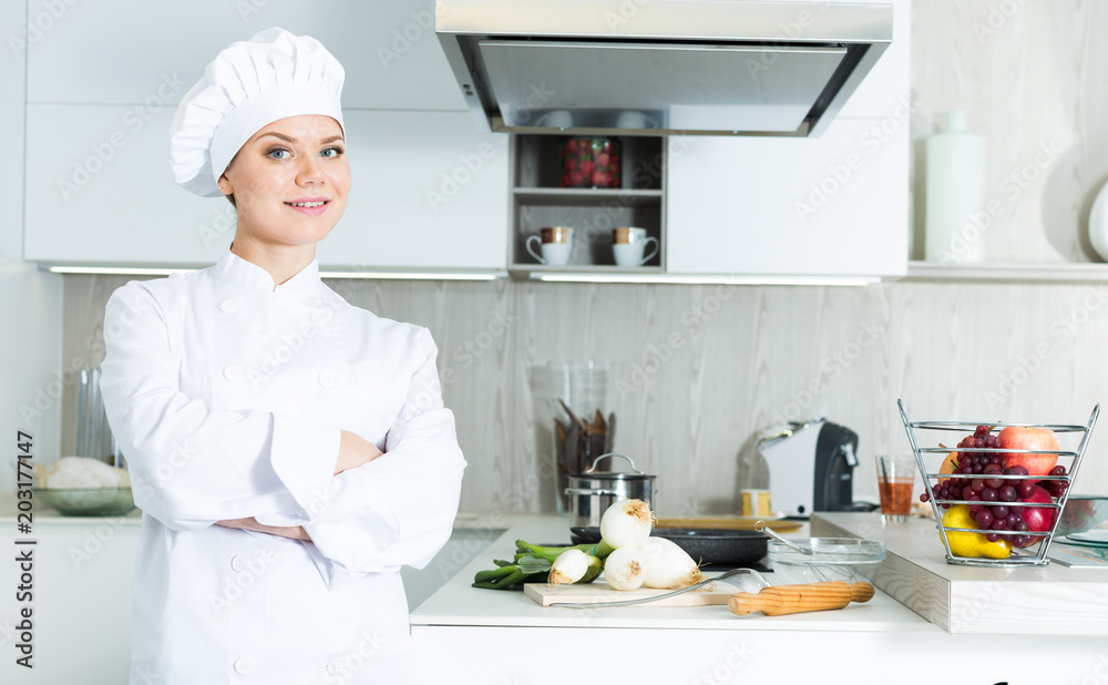 Portrait of the woman proffesional who is posing with devices in the kitchen