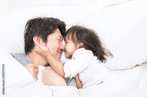 Father and daughter laughing and bonding in bed. Daddy and his little girl spending time at home. Fun love family lifestyle concept.