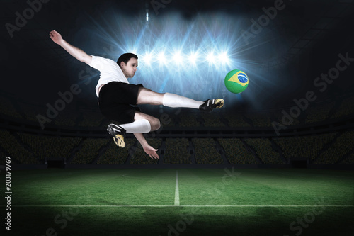 Football player in white kicking in a football pitch under spotlights © vectorfusionart