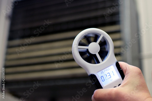 Hand-held anemometer measuring air flowing of ventilation louvres of the industrial ventilation unit. photo