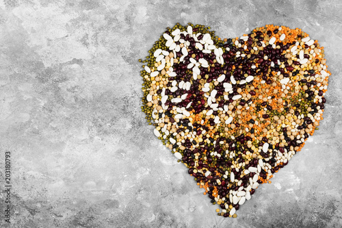 Assortment of beans (red lentil, green lentil, chickpea, peas, red beans, white beans, mix beans, mung bean) on gray background. Top view, copy space. Food background